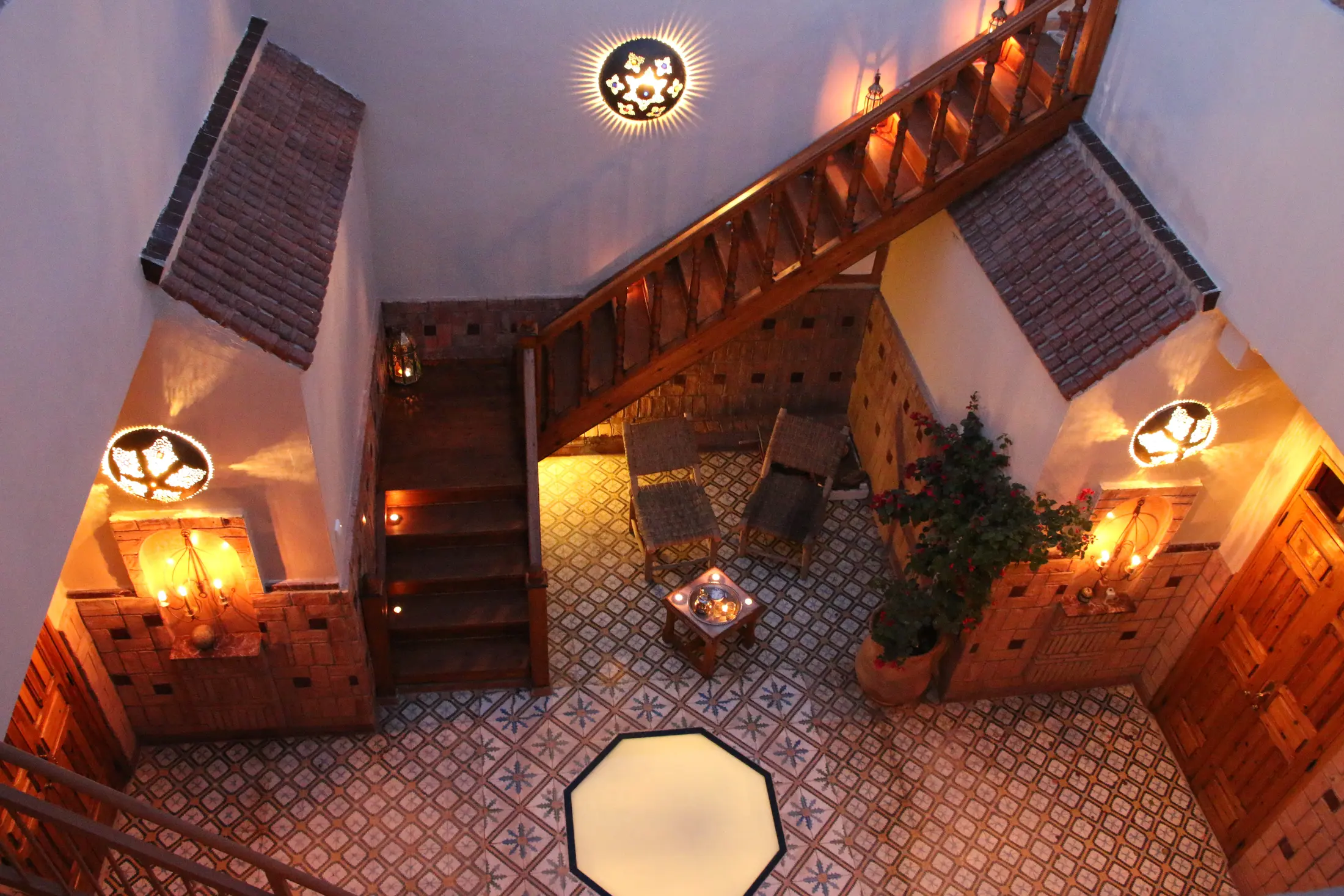 The zellige courtyard and lit cedar staircase at dusk