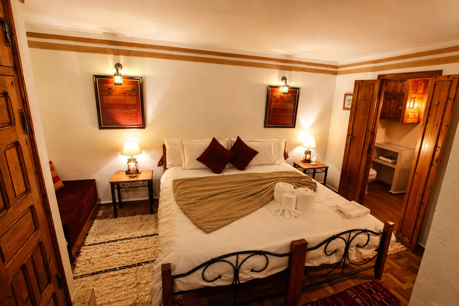 A wrought-iron bed with red cushions and wall lanterns